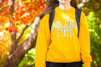 Student on campus in fall in Appalachian State sweatshirt. 